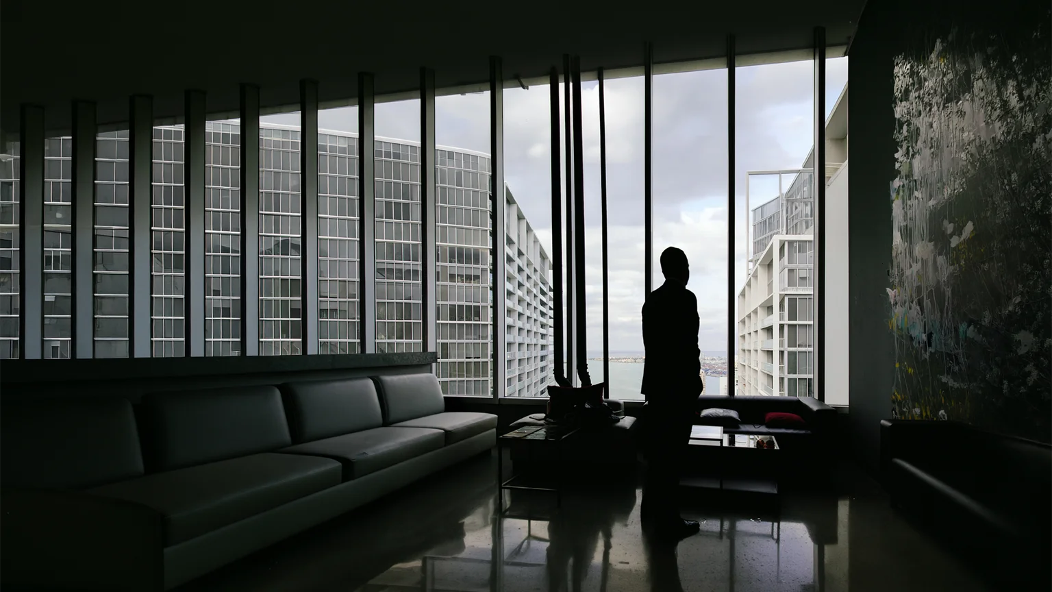Realtor silhouetted against floor-to-ceiling windows while showing a high-rise apartment in Brickell, Miami.