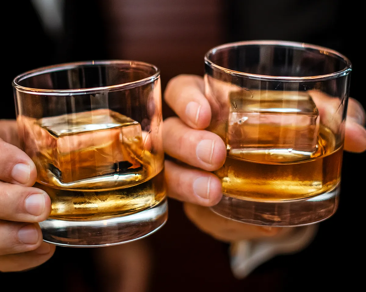 Two guests raising glasses of whiskey during the Chilled 100 Round Table event in Miami.
