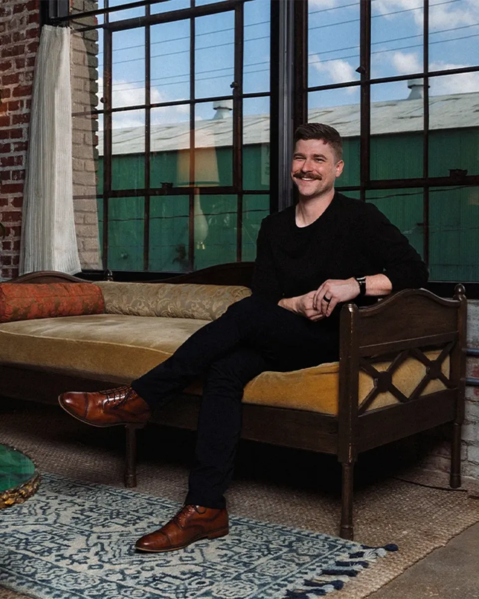 Darien Gibson of West Sky Studio seated in an editorial portrait inside a creative studio environment.