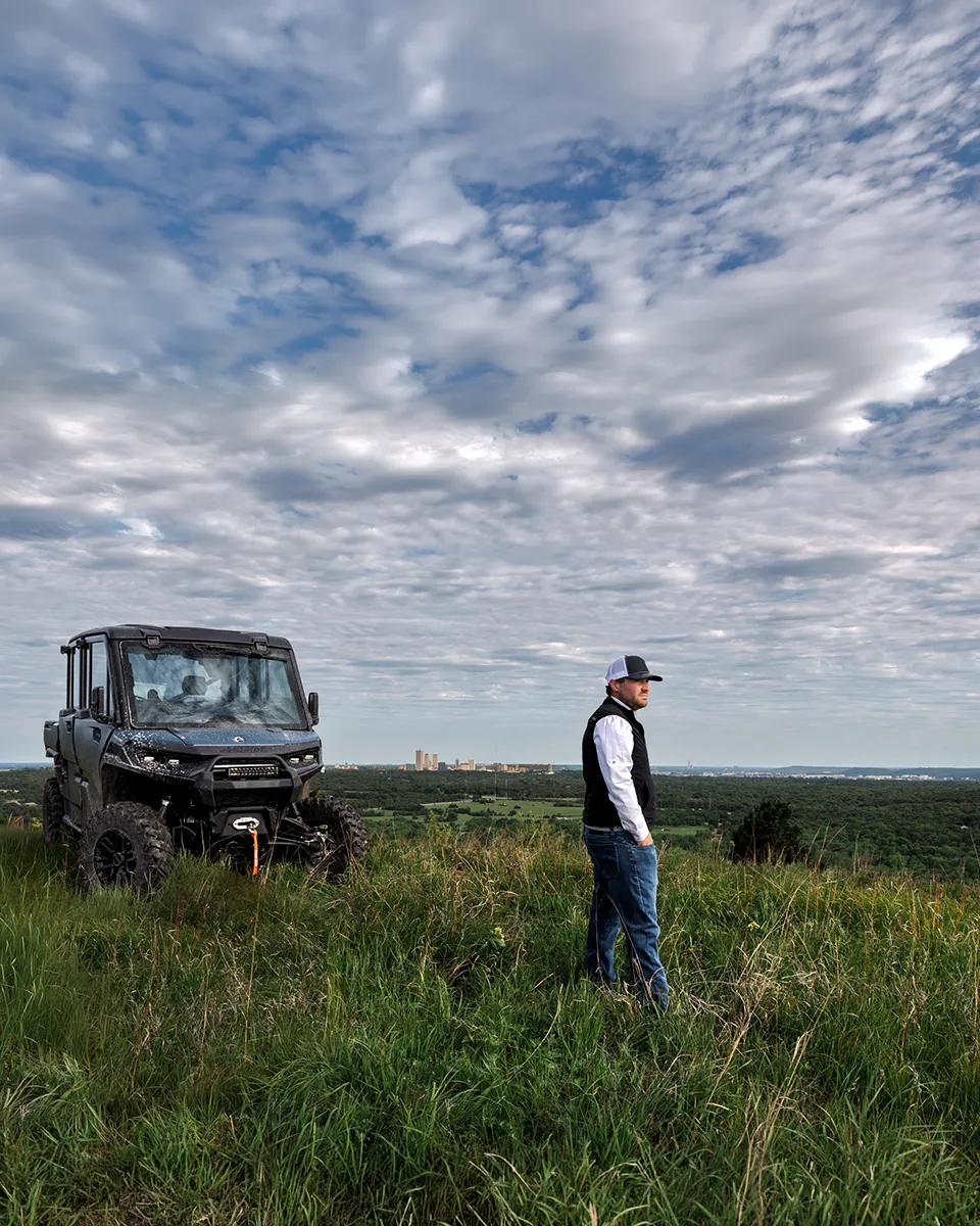 G7 Ranches Realtor JP Hewitt surveying a property at POSTOAK overlooking the Tulsa skyline beside his UTV.